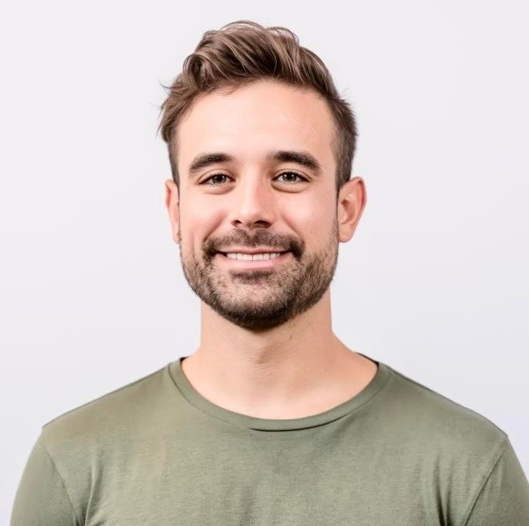 Smiling man in a green shirt against a plain background.
