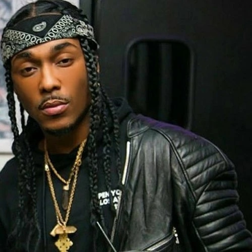 Person with braids wearing a leather jacket and bandana, accessorized with gold necklaces.